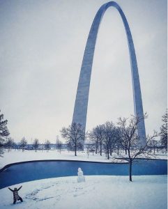 Someone builds a snowman in front of the Arch
