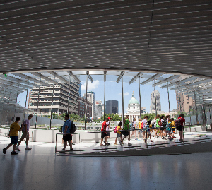 A number of guests walking around the Gateway Arch main entrance on Fee Free Day with a view of the Old Courthouse in the background.