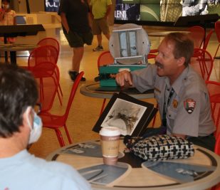 A National Park Service Ranger holds a photo of the construction of the Gateway Arch and speaks to guests during a Coffee with a Ranger event at Gateway Arch National Park. (Photo provided by NPS)