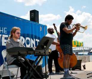 A three-piece band performs on a beautiful day on the St. Louis Riverfront during the Rockin' on the Riverfront event.
