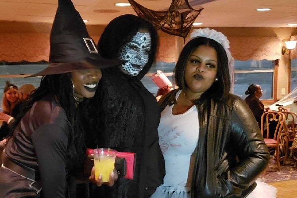 Four female guests are in Halloween costumes and pose for a photo on the Halloween Costume Party Cruise on the Riverboat.