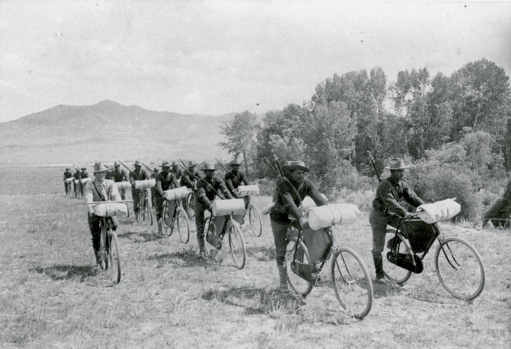 Historic black and white photo of the Iron Riders traveling across an open field. Image provided by National Park Service.