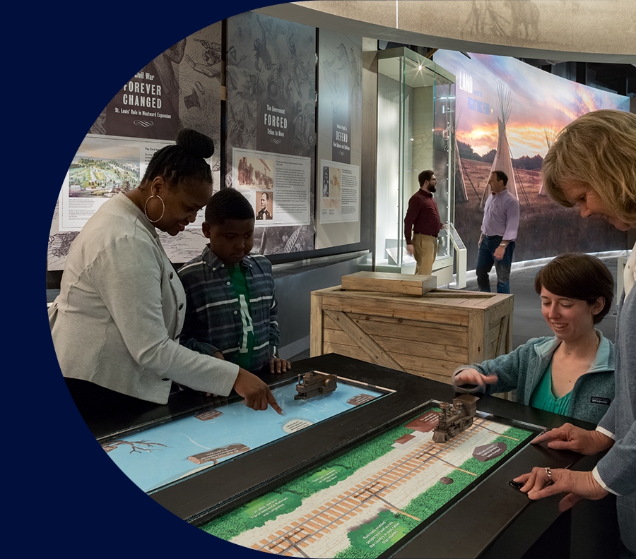 Visitors of the Museum under the Gateway Arch inspecting an exhibit.