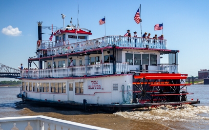 Tom Sawyer riverboat leaving the dock and cruising up the Mississippi River.