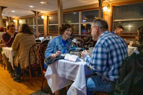 A couple smiles while eating at a table on a Skyline Dinner Cruise