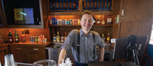 A smiling bartender on the Riverboats at the Gateway Arch server stands behind the bar