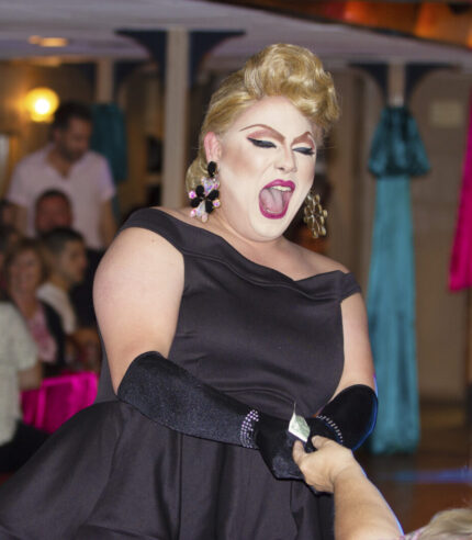 An entertainer takes money handed to them by a guest during a Decked Out Divas Cruise