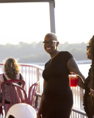 Young women enjoy drinks and dancing on the exterior deck of a Groove & Spin Cruise