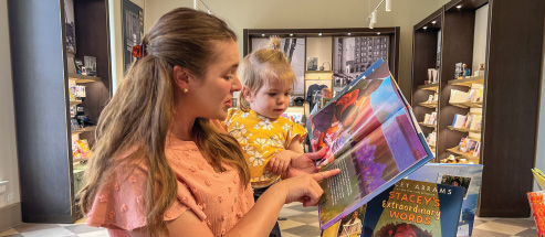 A mother holds her daughter and reads her a book inside the gift shop at the Old Courthouse
