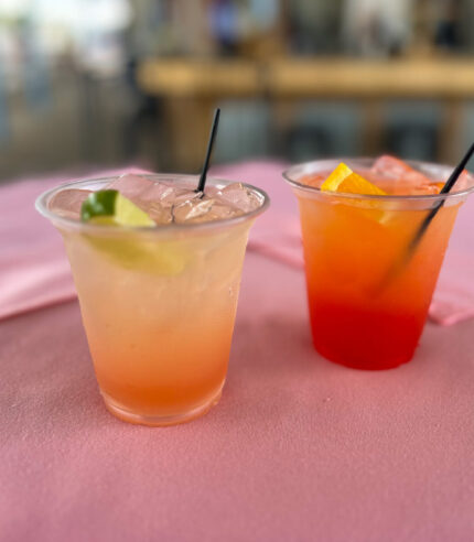 Two colorful tequila cocktails, the Mississippi River Sunrise and Sparkling Paloma, on a table.