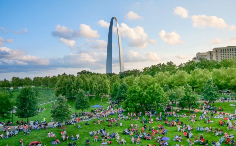 View of Gateway Arch National Park with hundreds of people sitting and watching a blues concert during Blues at the Arch Festival.