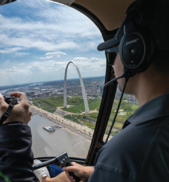 View from back seat of helicopter tour over the Mississippi River looking into downtown St. Louis and the Gateway Arch