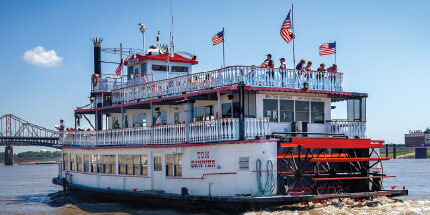 Tom Sawyer riverboat leaving the dock and cruising up the Mississippi River.