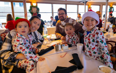 Family in PJs smiles for a photo during a PJs and Pancakes with Santa Cruise on the Riverboats at the Gateway Arch
