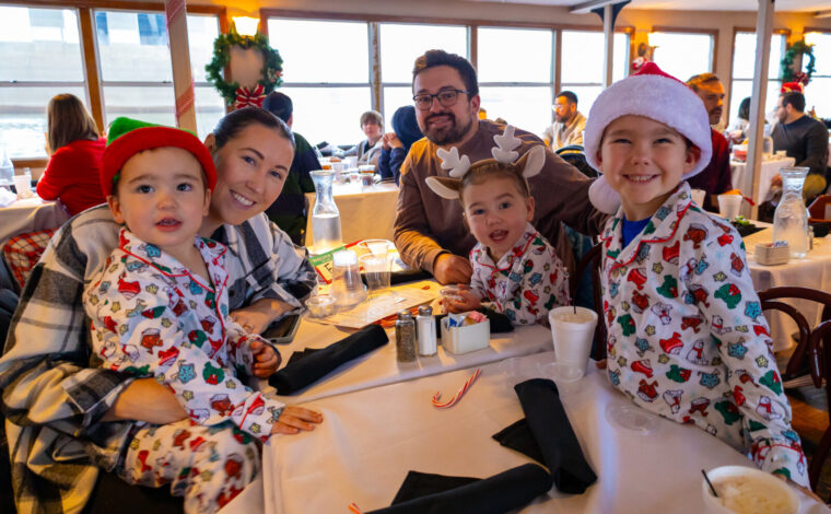 Family in PJs smiles for a photo during a PJs and Pancakes with Santa Cruise on the Riverboats at the Gateway Arch
