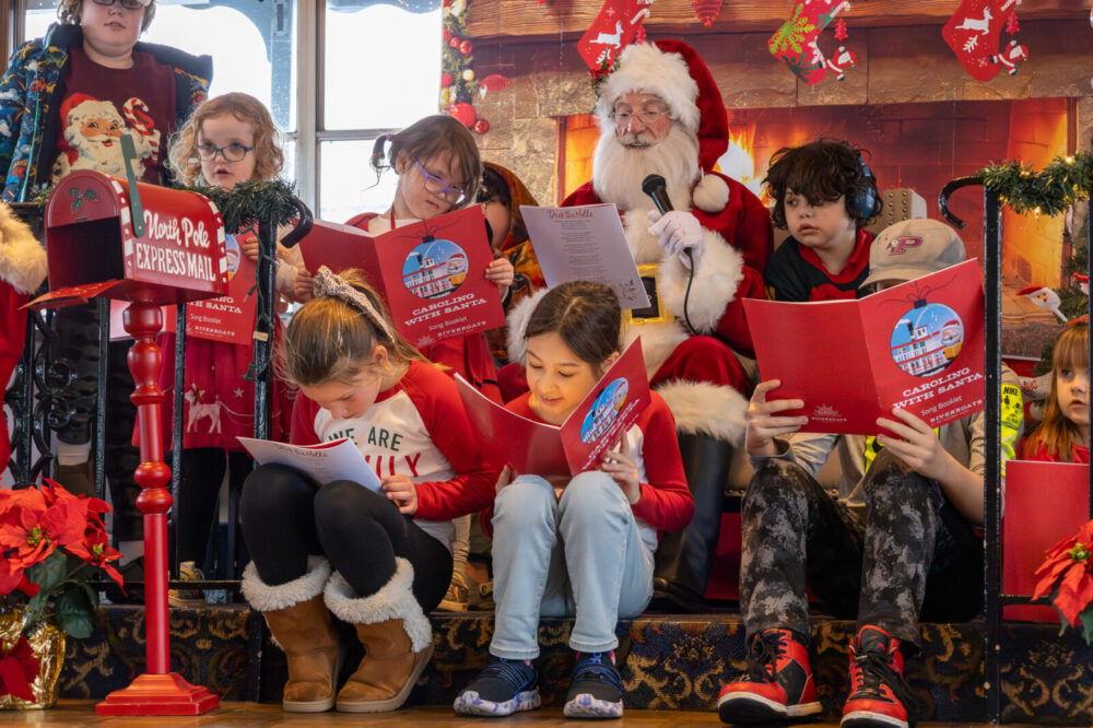 Children sit around Santa as they all sing Christmas songs during a Caroling with Santa Cruise on the Riverboats at the Gateway Arch