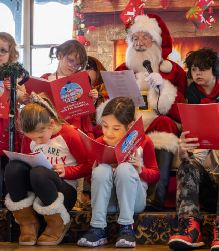 Children sit around Santa as they all sing Christmas songs during a Caroling with Santa Cruise on the Riverboats at the Gateway Arch