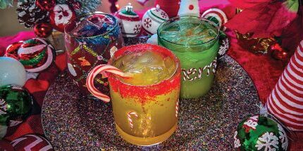 Three holiday drinks displayed on a festive table against a green background.