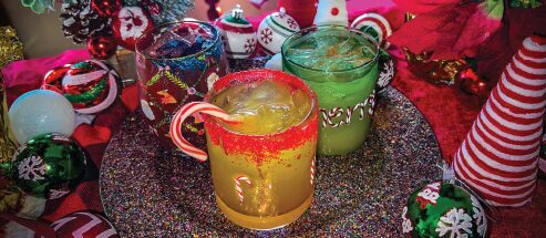 Three holiday drinks displayed on a festive table against a green background.