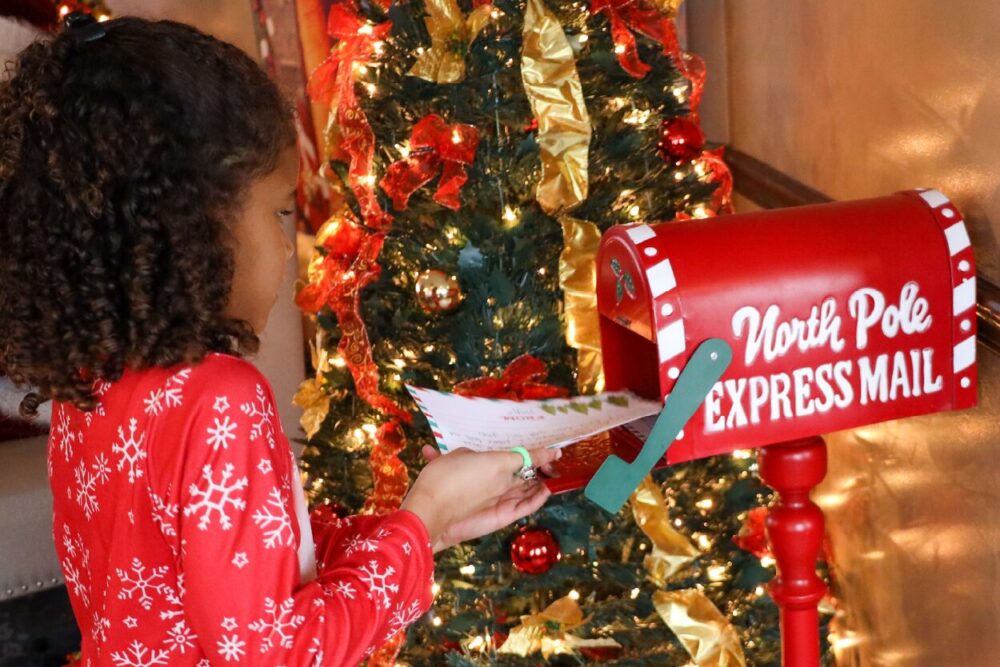young girl putting a letter to Santa in the mailbox