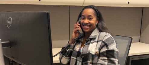 female staff member sitting behind a computer while talking on the phone.