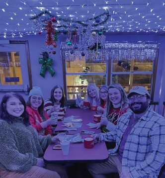 A table of young adults cheers at a table on The Floating Sleigh.