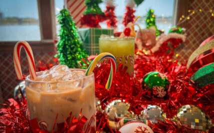 Multiple holiday drinks displayed on a festive table inside The Floating Sleigh holiday pop-up bar.