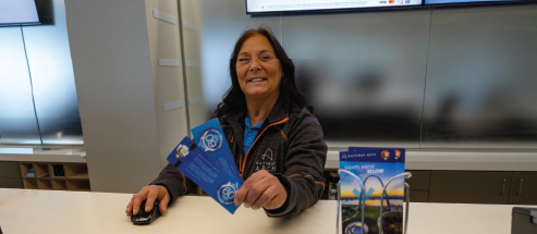 A Ticket Sales Agent at the Gateway Arch smiles as she hands out two tickets.
