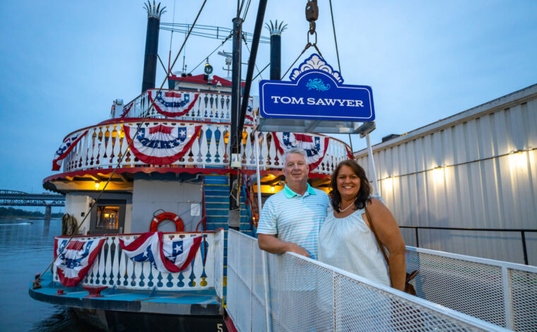 Couple poses for a photo while boarding the Tom Sawyer riverboat for a Skyline Dinner Cruise