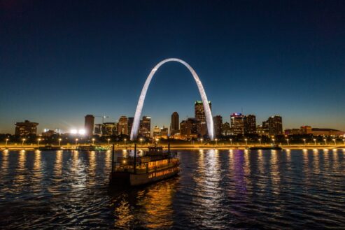 Aerial image of a riverboat in front of the illuminated Gateway Arch during a Skyline Dinner Cruise