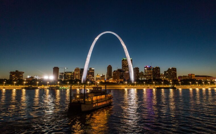 Aerial image of a riverboat in front of the illuminated Gateway Arch during a Skyline Dinner Cruise