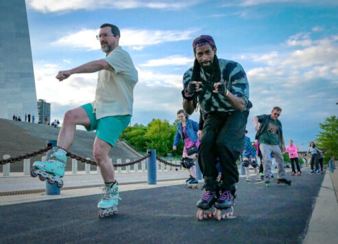 People roller skating on the St. Louis riverfront under the Gateway Arch.