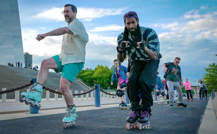 People roller skating on the St. Louis riverfront under the Gateway Arch.