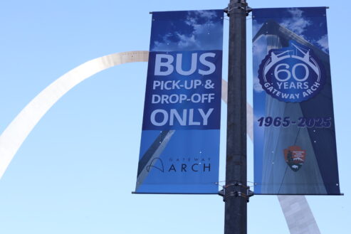 Image of banners for bus drop off and pick up lane in front of the Gateway Arch.